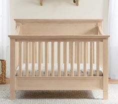 a baby crib in front of a window with white curtains