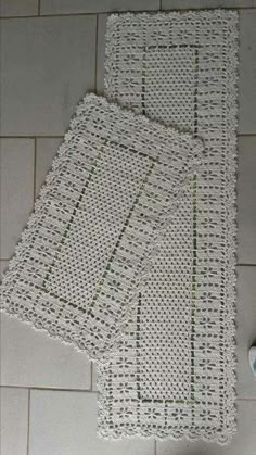 two pieces of white crochet on a tile floor with the words knitted