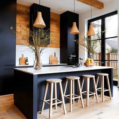 a kitchen with black cabinets and wooden stools