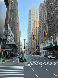 an empty city street with traffic lights and tall buildings in the background on a sunny day