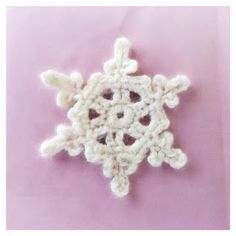 a crocheted snowflake on a pink background