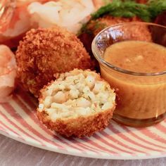 a plate with some food on it next to a bowl of dipping sauce and shrimp