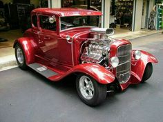 an antique red car parked in front of a building