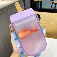 a person holding up a plastic case with two fish in it's water inside