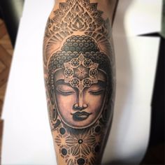 a person with a tattoo on their leg that has a buddha head in the middle