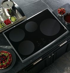 a black stove top sitting on top of a counter next to cups and saucers