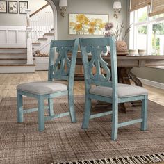 two blue chairs sitting on top of a rug in front of a dining room table