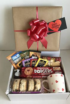 an open box filled with cookies, candy and other items next to a coffee mug