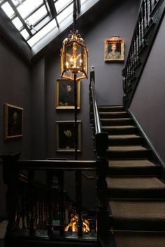 a staircase with pictures on the wall and a light fixture