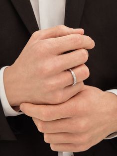 a man in a suit and tie wearing a wedding band with a diamond ring on his finger