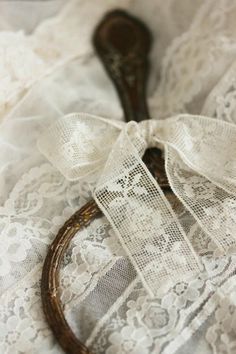 an old wooden spoon sitting on top of a lace covered table cloth with a ribbon tied around it