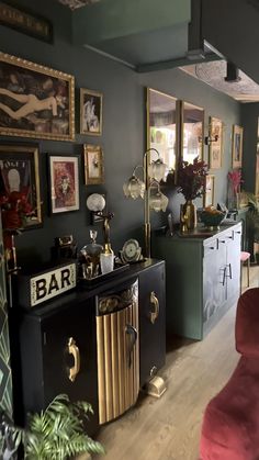 a living room filled with furniture and pictures on the wall next to a bar area