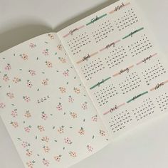 an open calendar book with floral designs on the pages and numbers in pink, green and blue