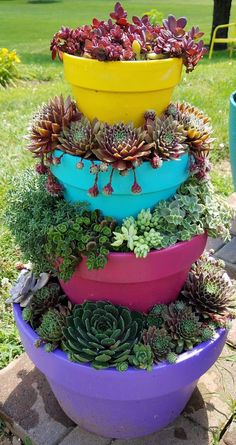 a stack of colorful pots filled with succulents