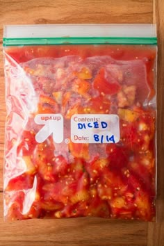 there is a bag of diced tomatoes on the wooden table and it has two labels