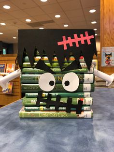 a stack of books sitting on top of a table covered in paper and fake eyes