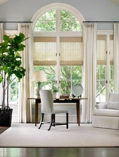 a living room filled with furniture and a large window covered in white drapes