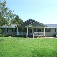 a gray house sitting on top of a lush green field