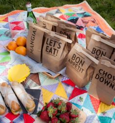 several bags with words on them are sitting on a blanket next to fruits and vegetables