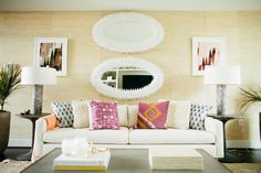 a living room filled with lots of furniture and mirrors on the wall above it's headboard