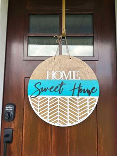 a wooden sign that says home sweet home hanging on the front door with a key