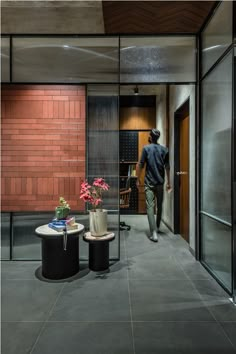 a man is walking through an office building with two tables and chairs in front of him