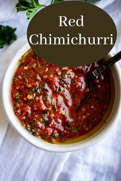 a white bowl filled with red chili sauce and garnished with parsley