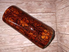 a brown glass vase sitting on top of a wooden table next to a white wall