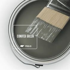 a paint can with a brush in it and the words conifer green on top