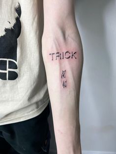 a person with a tattoo on their arm that says trick and a dog is in the background