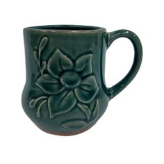 a green coffee mug with a flower design on the outside and inside, sitting in front of a white background