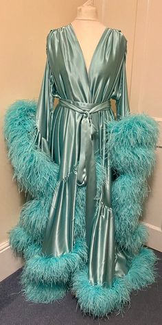 Beautiful chiffon dressing gown in Lagoon Breeze.  100% silk satin trimmed along the hem and the sleeve edges with luxurious ostrich feathers.  Fastens around the waist with a matching silk belt.  One size fits all due to the design, fullness and fabulousness of the robe.  Perfect for family gatherings, walking the dogs as well as taking out the rubbish. Please expect some feathers to shed - no one can look this fabulous without losing a few feathers. Long Sleeve Feather Robe For Parties, Elegant Feathered Evening Robe, Satin Dresses With Feather Trim, Elegant Satin Robe With Feathers, Walking The Dogs, Feather Gown, Satin Dressing Gown, Feather Coat, Ostrich Feather Trim