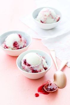 three bowls filled with ice cream on top of a pink tablecloth next to spoons