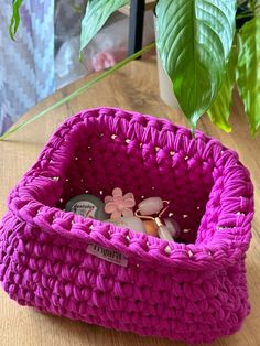 a pink crocheted basket sitting on top of a wooden table