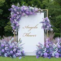 purple flowers and greenery surround a white sign