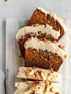 slices of carrot cake with cream cheese frosting and walnuts on white parchment paper