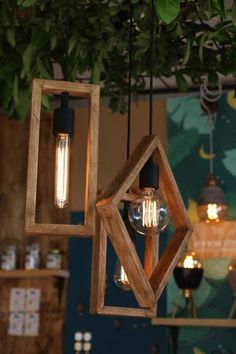 two wooden lights hanging from the ceiling in a room with green plants and other decorations