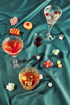 two glasses of wine and some candy on a blue cloth