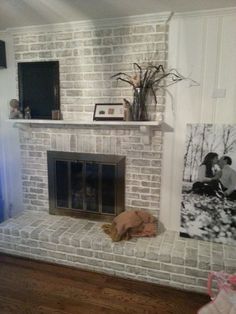 a living room with a brick fireplace and pictures on the wall, along with wood flooring