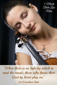 a woman holding a violin in her right hand and looking down at the strings on her left shoulder