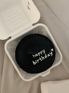 a black birthday cake in a white container