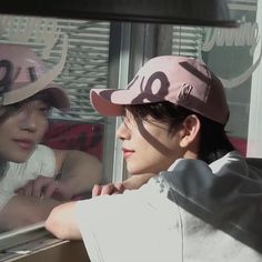 a woman in a pink hat looking out the window at another person wearing a white shirt