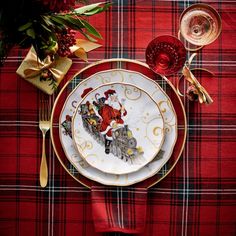 a plate with santa clause on it sitting on a plaid table cloth next to silverware