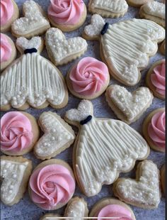 decorated cookies with pink frosting and white icing in the shape of dresses, hats, and flowers