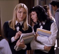 two women standing next to each other holding books