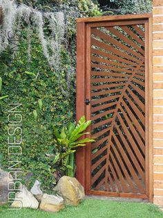 an image of a wooden gate in front of a wall with plants and rocks on it