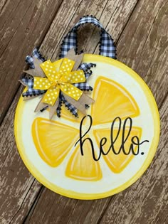 a yellow plaque that says hello on it with a bow around the edge and an orange slice