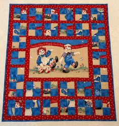 a blue and red patchwork quilt with two teddy bears playing on it's sides