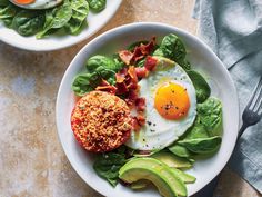 two bowls filled with eggs and spinach on top of a table