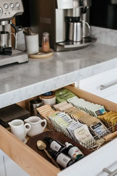 an open drawer in a kitchen next to a coffee maker and other items on the counter